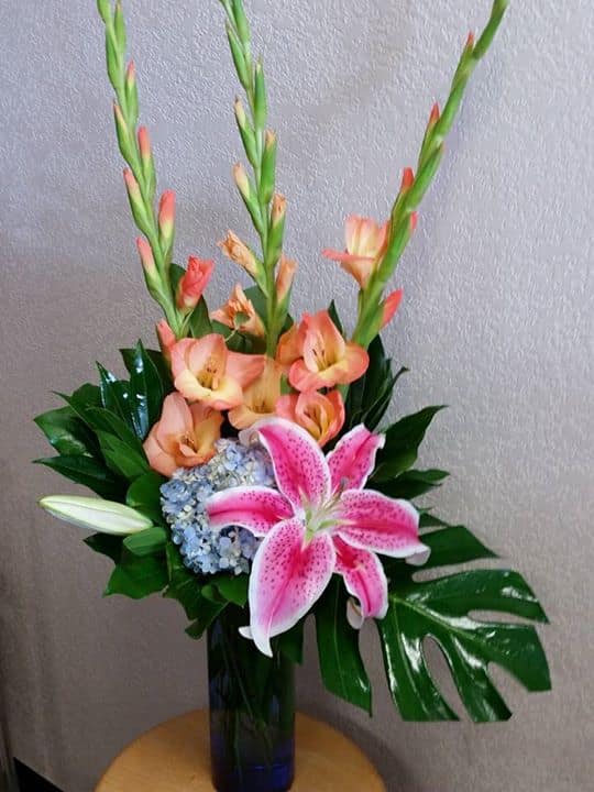 Pink lily and peach gladiolus arrangement in a blue vase