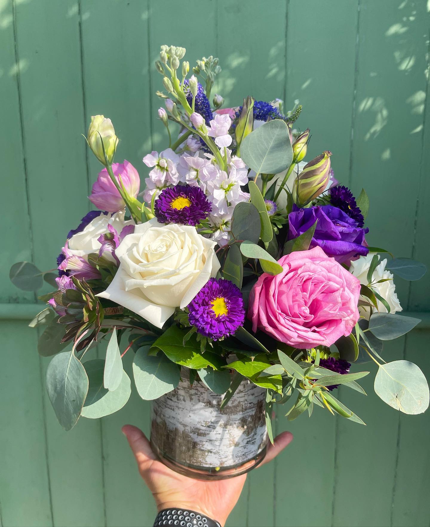 Mixed bouquet of roses and purple flowers in a glass vase