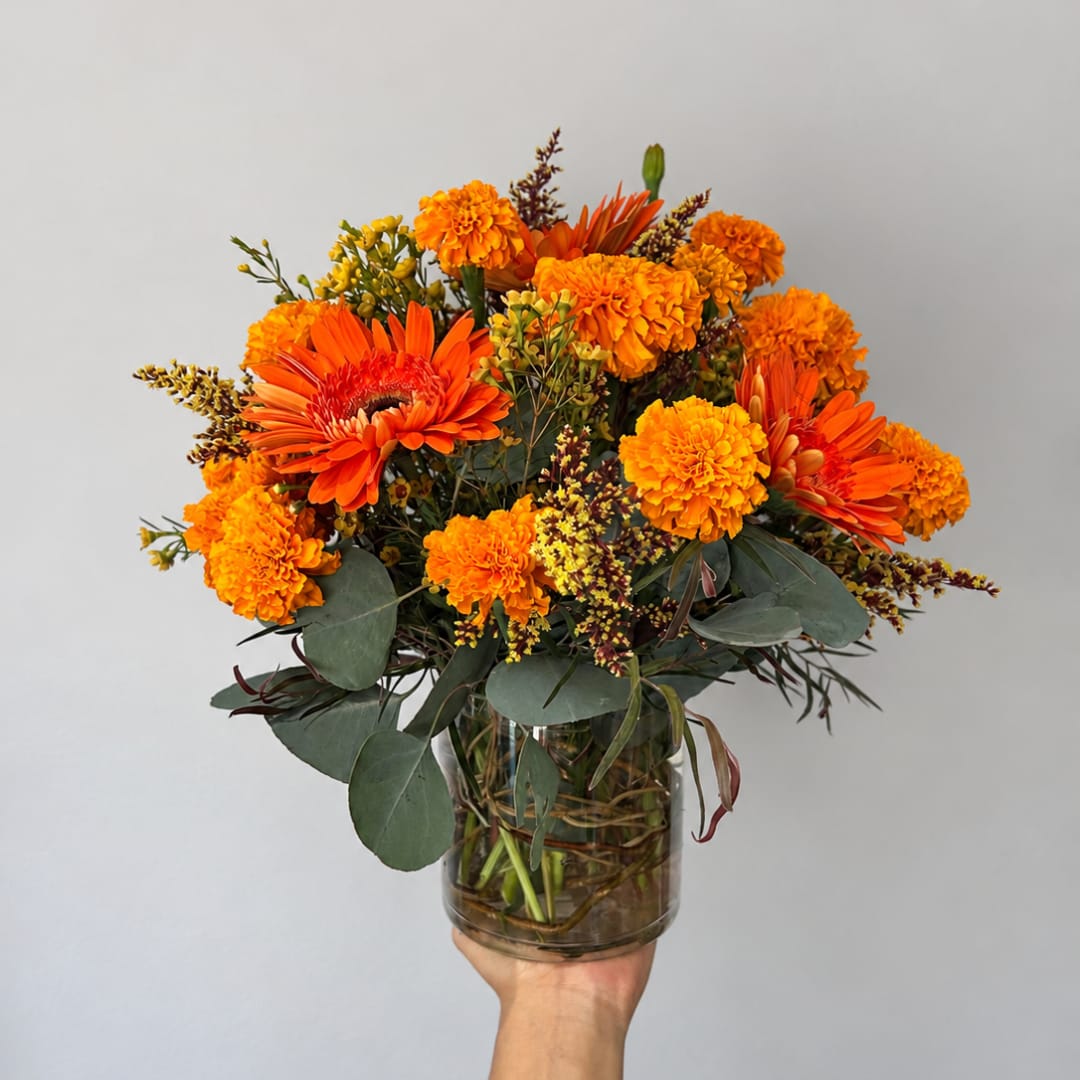 Orange and yellow mixed bouquet in a clear glass vase