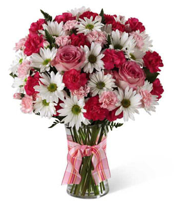 Pink and white mixed bouquet in a clear glass vase with a pink ribbon