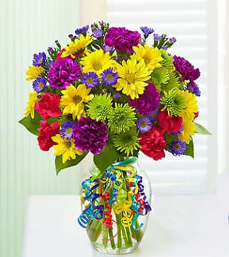 Colorful mixed bouquet in a clear glass vase with curly ribbon