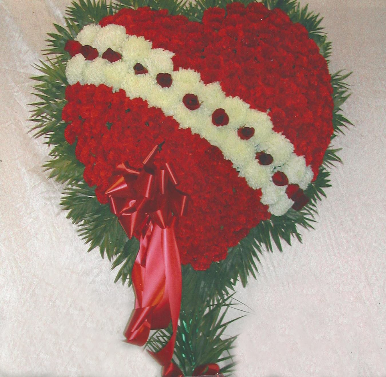Heart-shaped red and white floral arrangement with a red ribbon