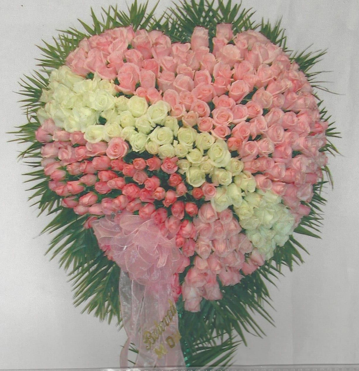 Heart-shaped floral arrangement of pink and white roses with a pink ribbon
