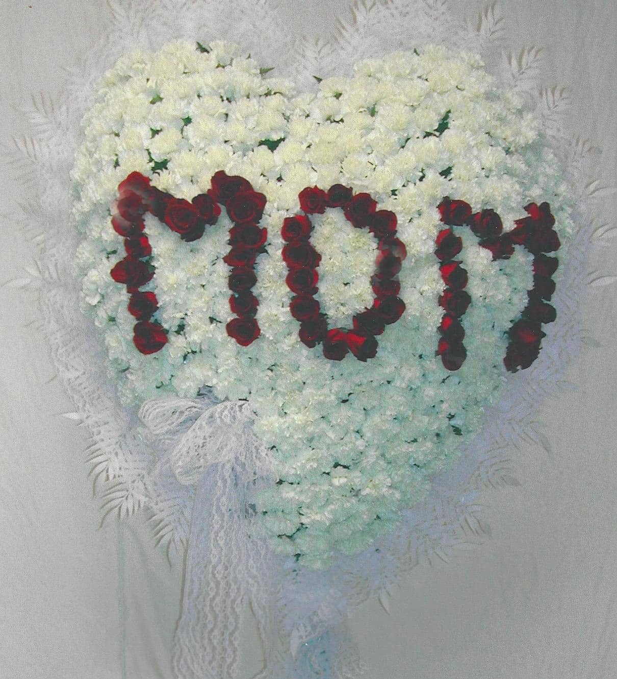 Heart-shaped white floral arrangement with red rose letters and lace ribbon