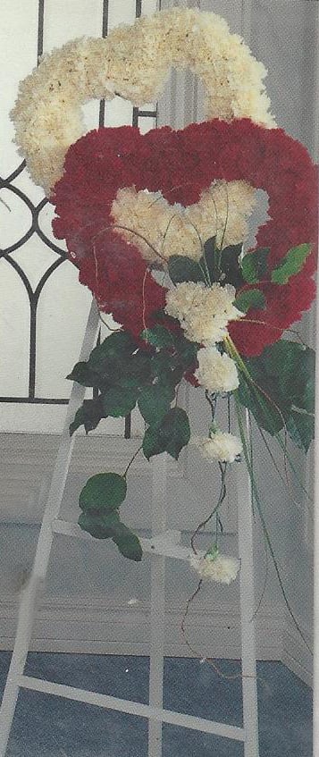 Heart-shaped floral wreath of red and white carnations on a stand