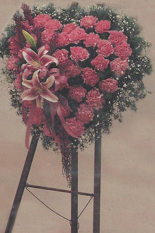 Pink carnation standing spray with lilies on a black easel