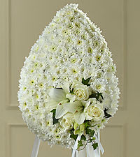 White funeral spray with lilies and roses on a standing easel