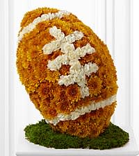 Orange and white floral arrangement shaped like a football on a green base