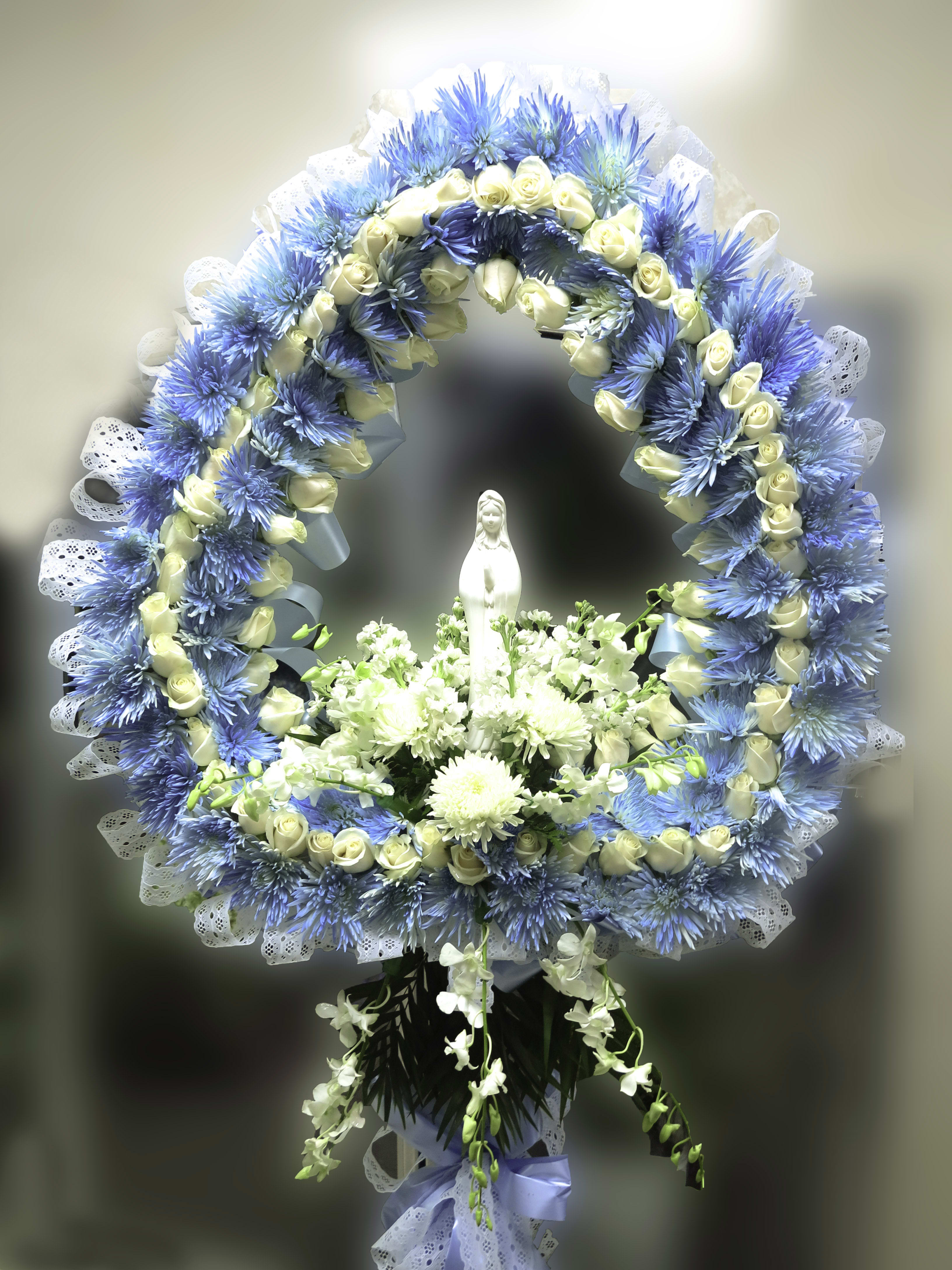 Blue and white floral funeral wreath with a small statue in the center