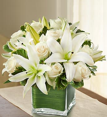White lilies and roses arranged in a square glass vase