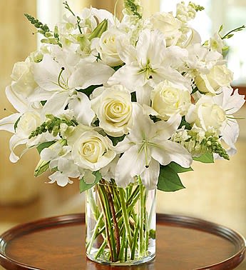 White lilies and roses arranged in a clear glass vase