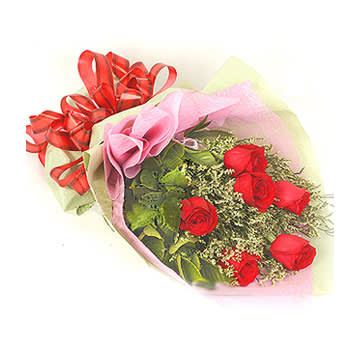Bouquet of red roses wrapped in pink and pale yellow paper with a red ribbon