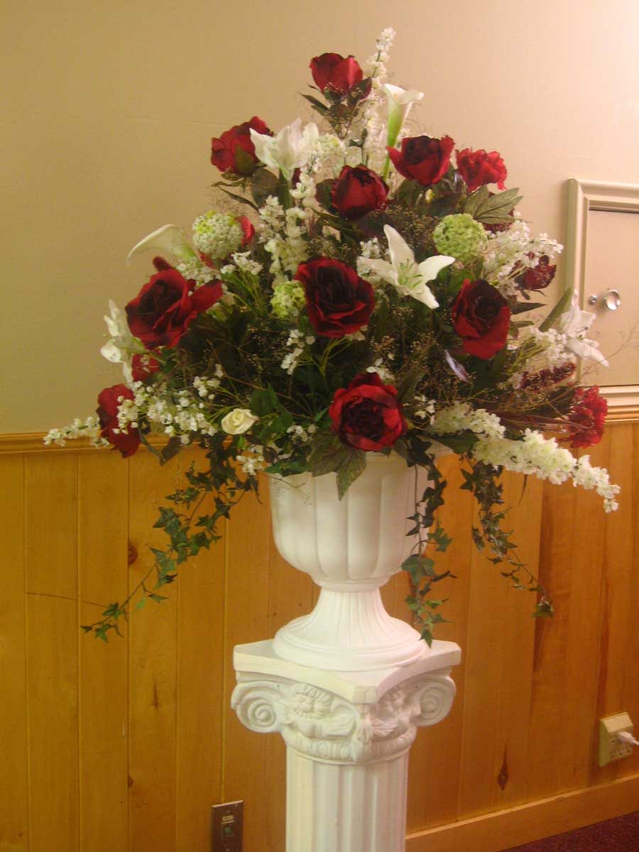 Red roses and white lilies arranged in a white pedestal vase