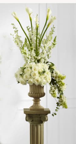 Tall white floral arrangement in a decorative urn on a pedestal