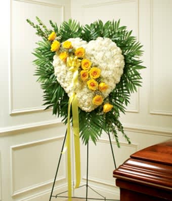 Heart-shaped white floral spray with yellow roses on a stand