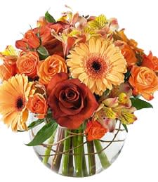 Bouquet of orange and yellow flowers in a clear glass vase