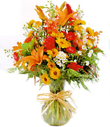 Bright orange and yellow mixed bouquet in a glass vase with a ribbon