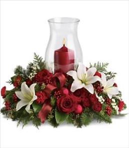 Red floral centerpiece with a candle in a glass hurricane vase