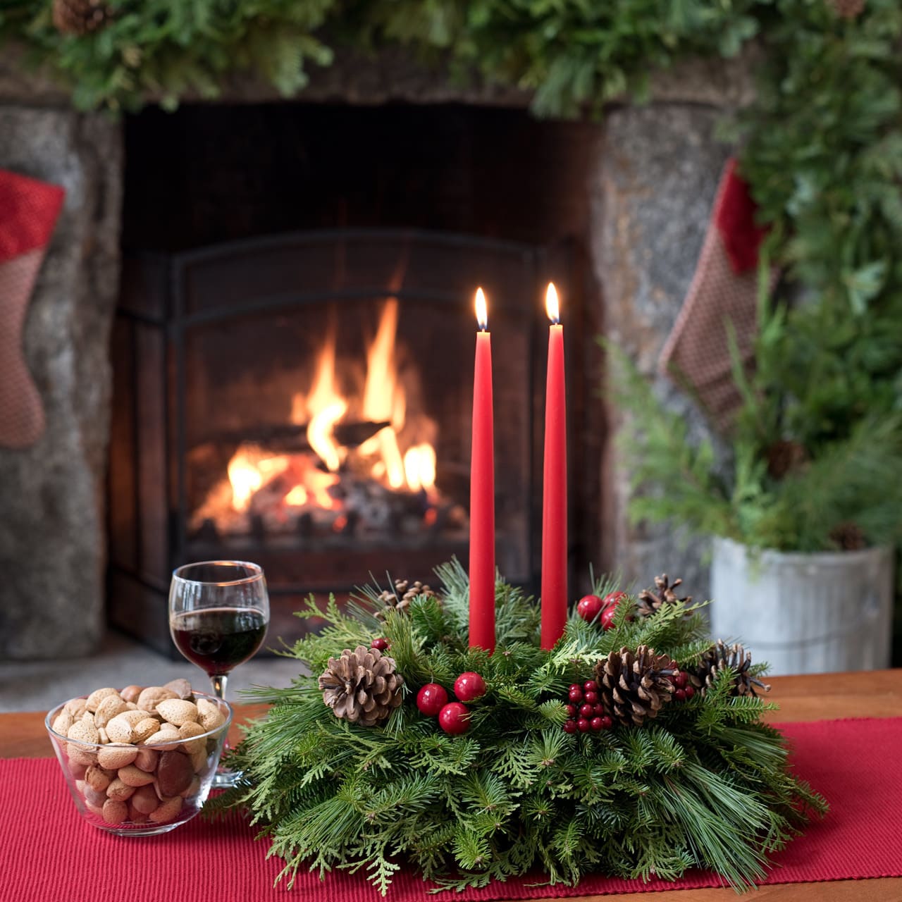 Holiday centerpiece with red candles, pinecones, and evergreen branches on a table