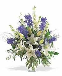 White lilies and purple flowers in a clear glass vase