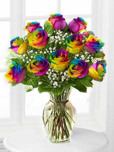 Rainbow roses arranged in a clear glass vase