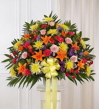 Large colorful floral standing spray with a yellow ribbon