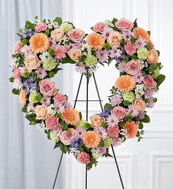 Heart-shaped floral wreath on a black easel with pastel flowers