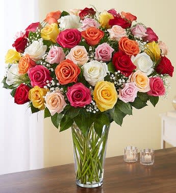 Mixed roses in many colors arranged in a clear glass vase