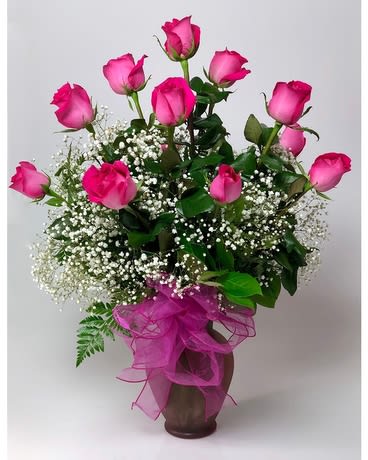Pink roses in a vase with baby's breath and a pink ribbon