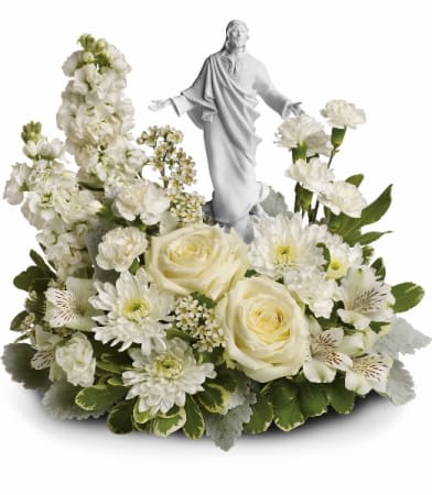 White floral arrangement with a small religious statue in the center