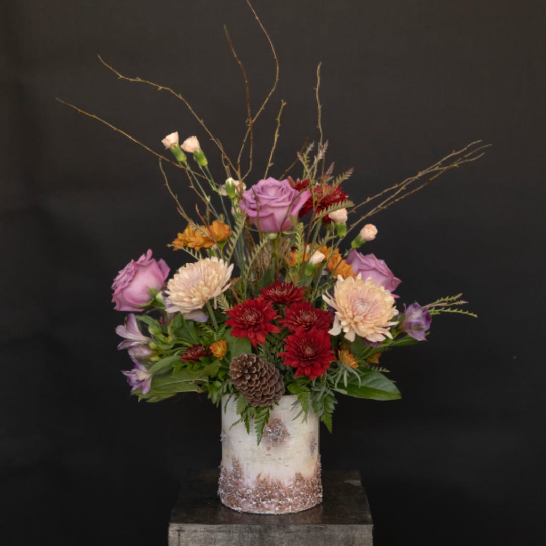 Mixed bouquet in a white vase with pink, red, and peach flowers