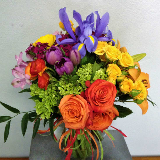 Colorful bouquet of roses, irises, and mixed blooms in a glass vase