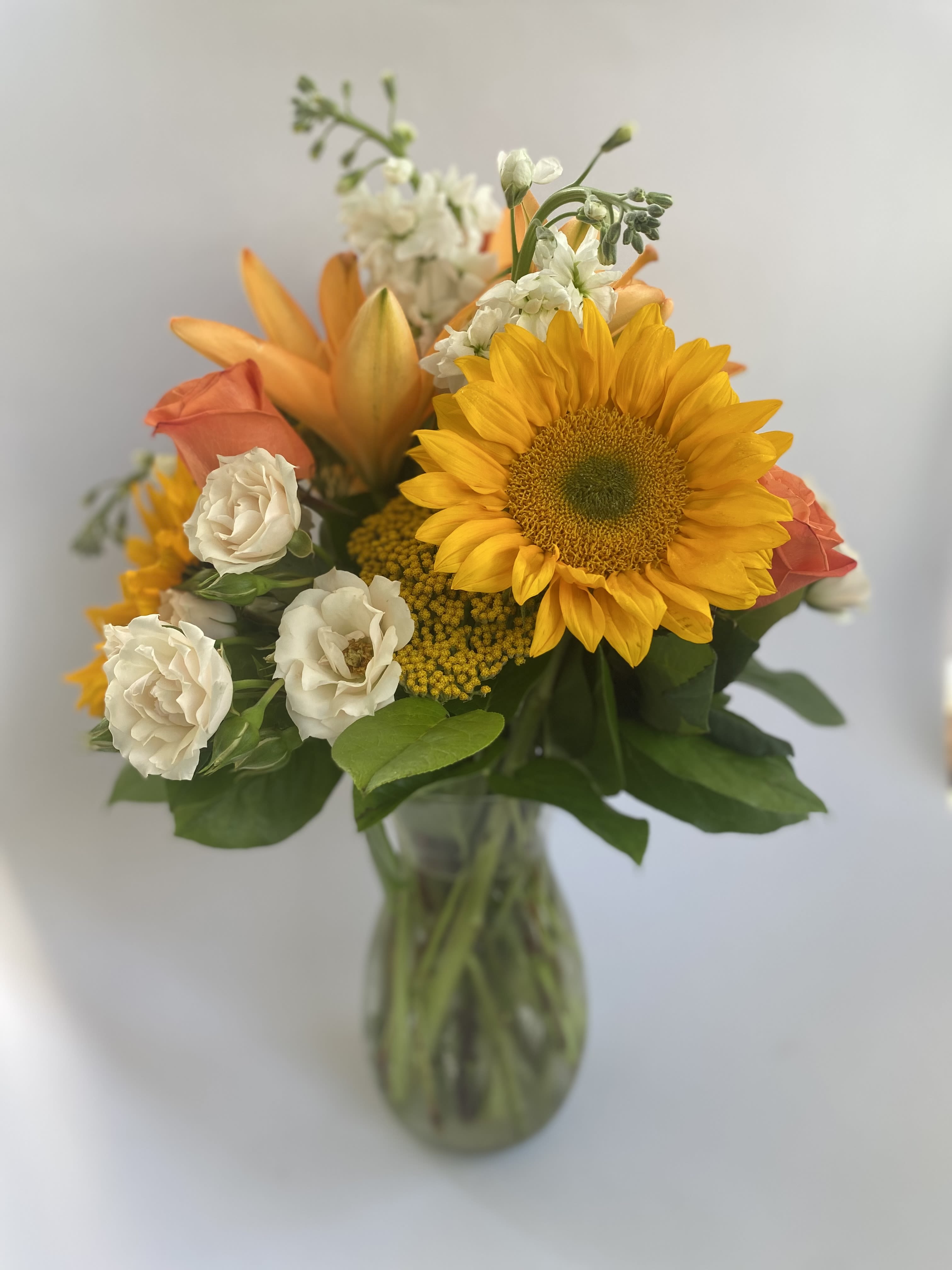 Fall Fresh - Embrace the Season with Fall Fresh Celebrate the vibrant beauty of autumn with our "Fall Fresh" arrangement, designed to bring warmth and cheer to any occasion. This fresh-cut, fall-themed bouquet is perfect as a hostess gift for gatherings, a comforting gesture for a loved one in the hospital, or simply to say, “thinking of you!” Elegant Glass Vase: A sophisticated vessel that enhances the display and fits seamlessly into any setting. Lush Greenery: Adds a rich, verdant base that highlights the colorful blooms. Spray and Standard Roses: Offer timeless elegance and layers of beauty. Lilies and Stock: Introduce a delightful fragrance and refined touch. Cheerful Sunflowers: Brighten the arrangement with their sunny charm. Yarrow: Provides unique texture and depth, embodying the essence of fall. Each element of "Fall Fresh" is meticulously selected to create a harmonious blend of autumnal colors and textures, making it a perfect choice for celebrating the season. Share the joy of fall with this exquisite arrangement from Elizabeth's Garden.