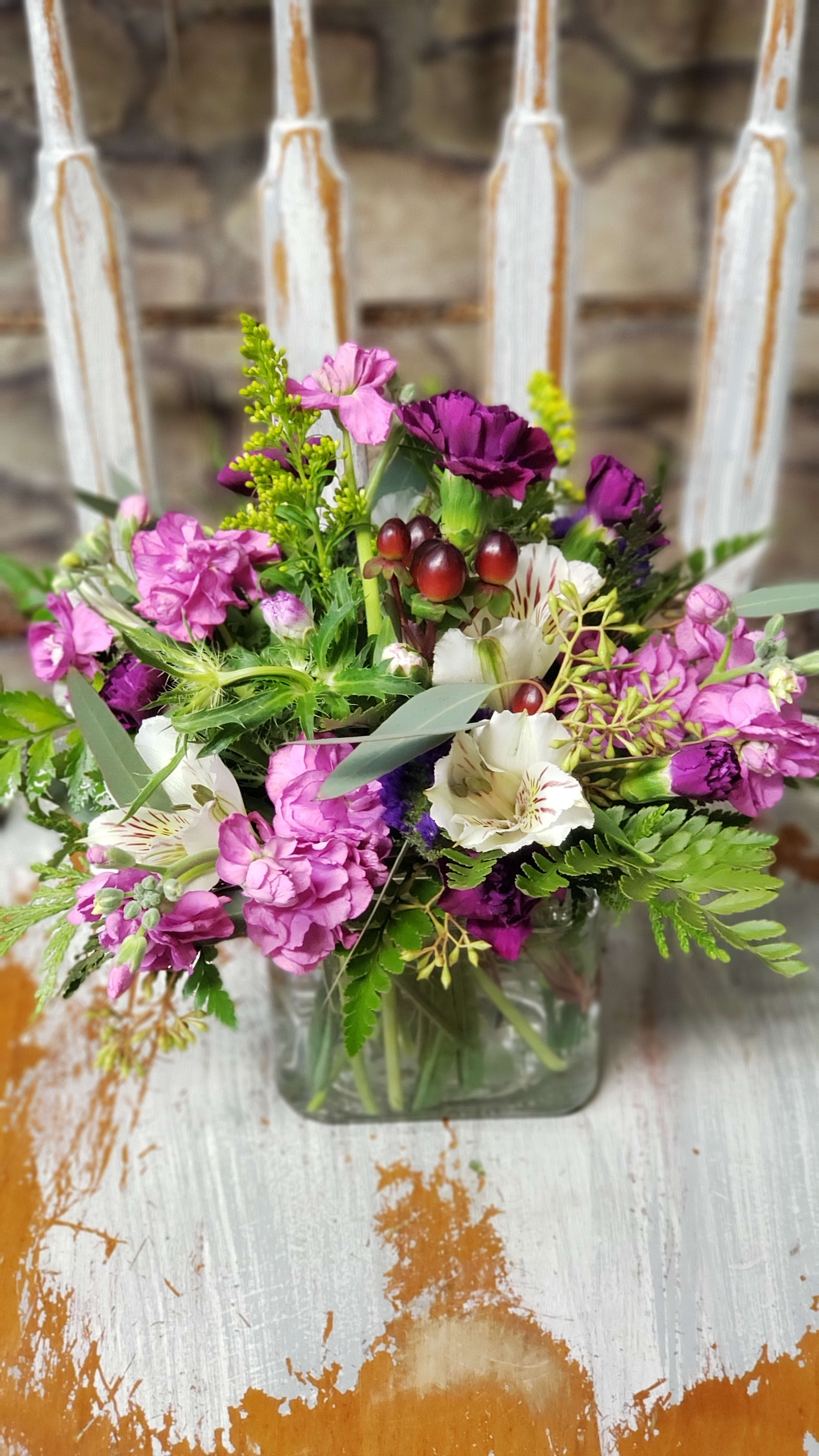 Pink and purple mixed bouquet in a square glass vase