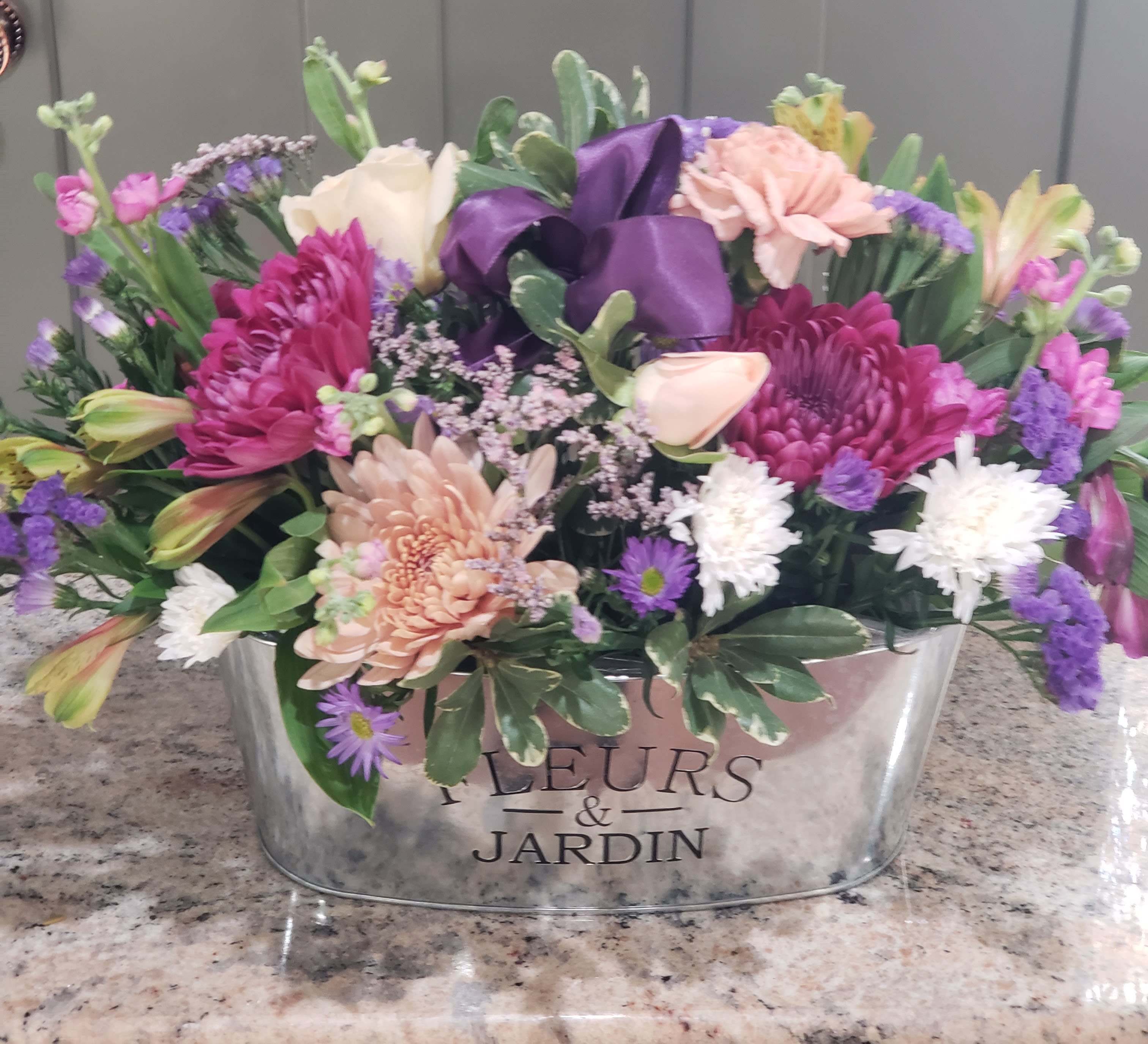  Flower Lane - NOTE! Limited qty of containers and blush tone flowers...would substitute!  Keepsake, oval tin container. Variety of colors and flowers in a oval-shaped style. Each design is customized with a variety of flowers, one of a kind, similar color theme. Limited availability for container. Order soon!