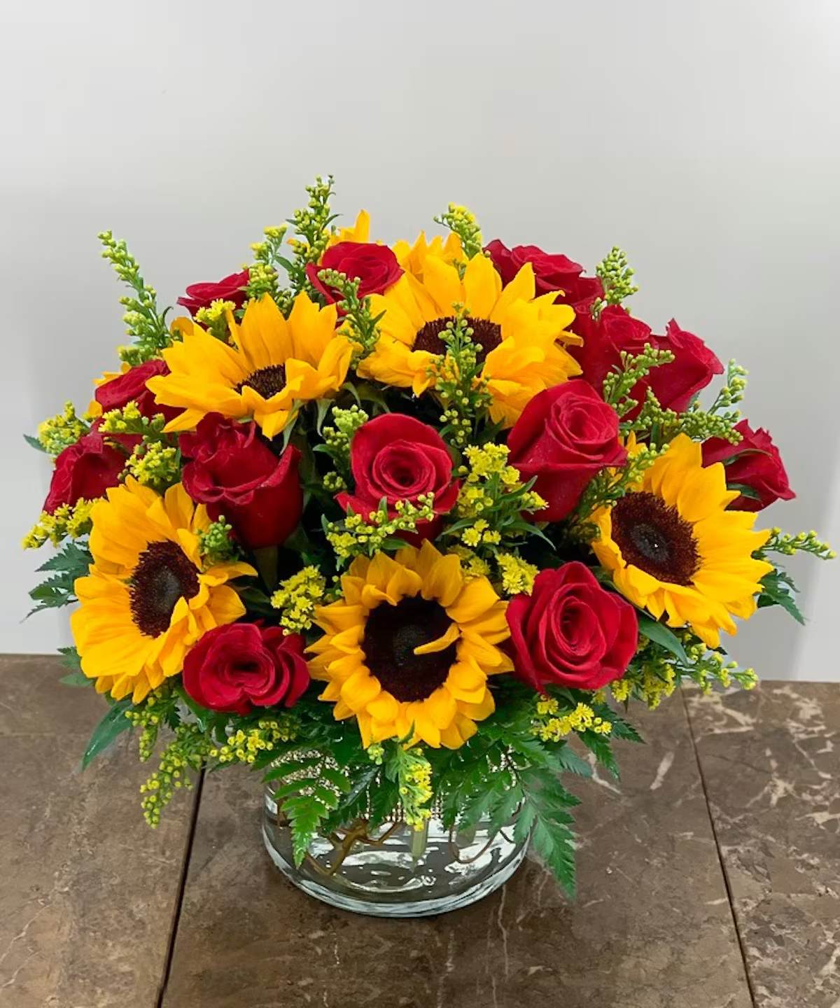 Love &amp; Sunshine - A cylinder brimming with Premium Red Roses and Sunflowers. It is accented with yellow solidago and premium greens. A unique gift for a momentous occasion, such as a birthday, anniversary, or to Say I Love You.  Note: The yellow solidago may be substituted with baby's breath as needed. 