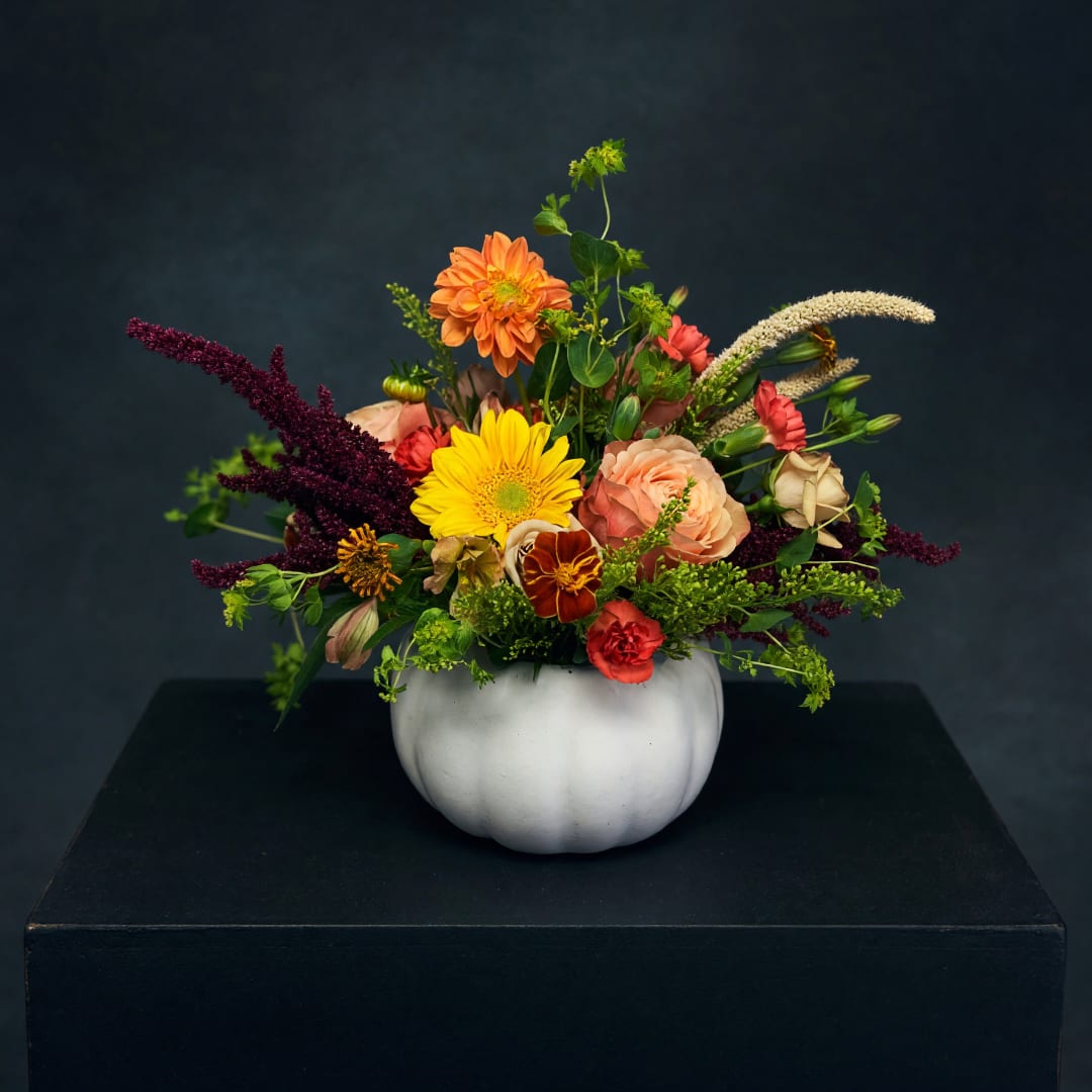 Mixed bouquet in a white pumpkin vase with orange, yellow, and pink blooms