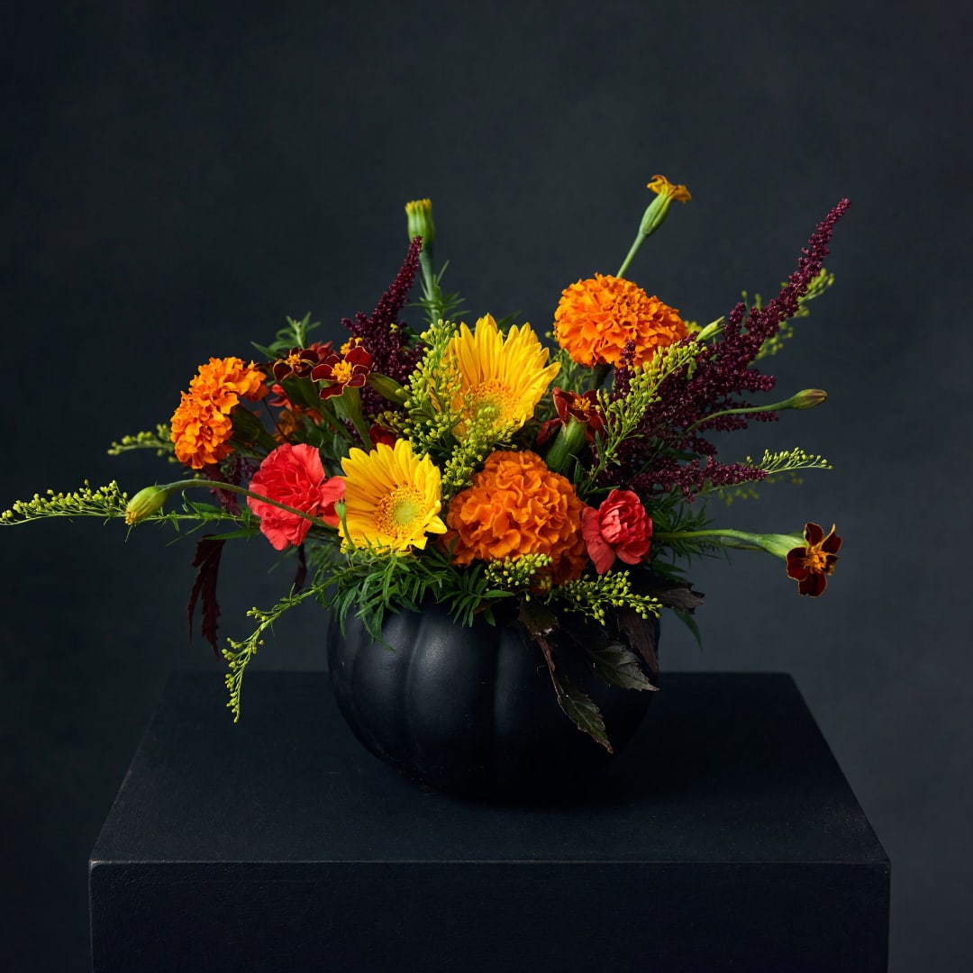 Orange and yellow mixed flower arrangement in a black vase