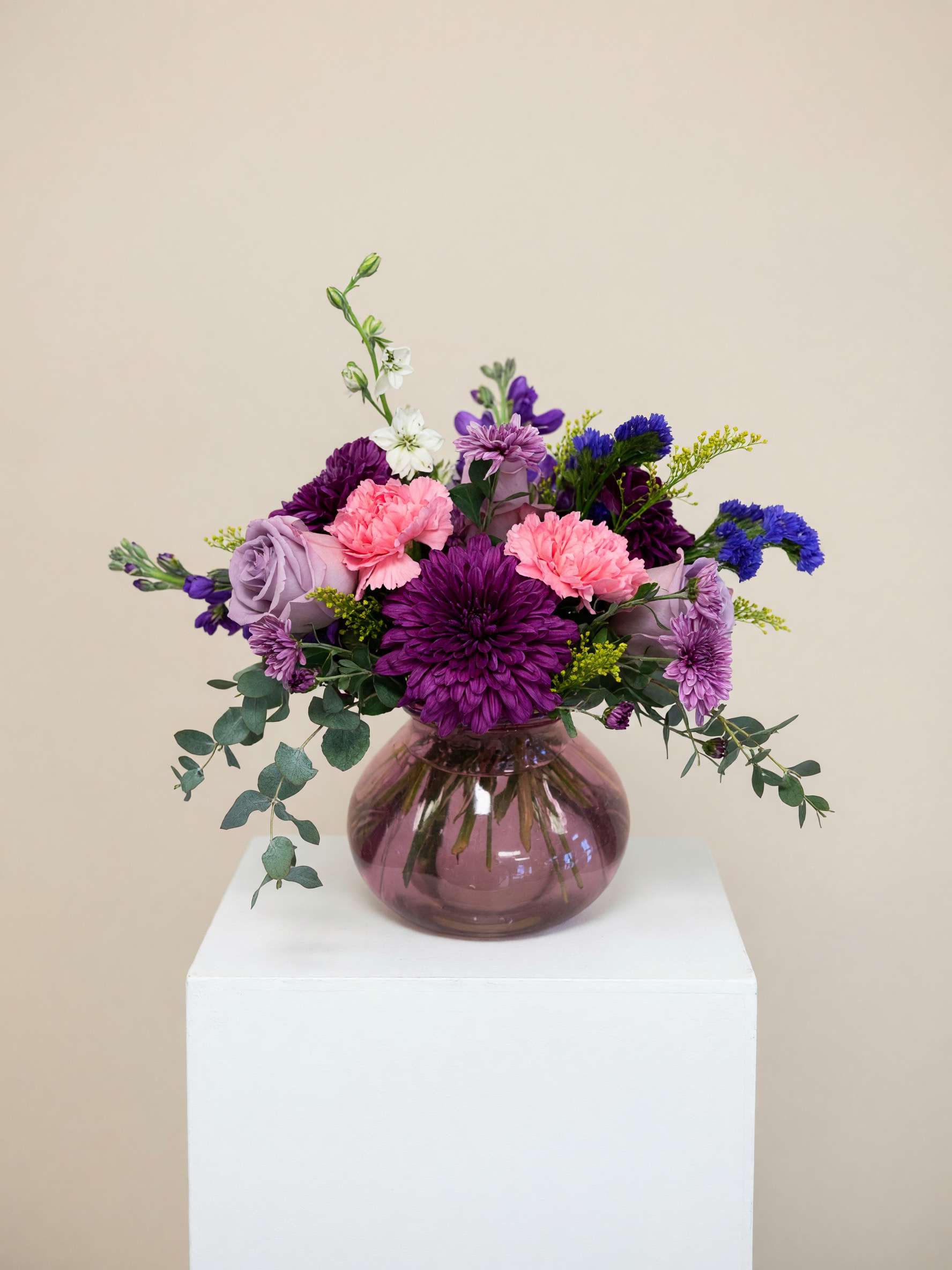 Purple and pink mixed bouquet in a round glass vase