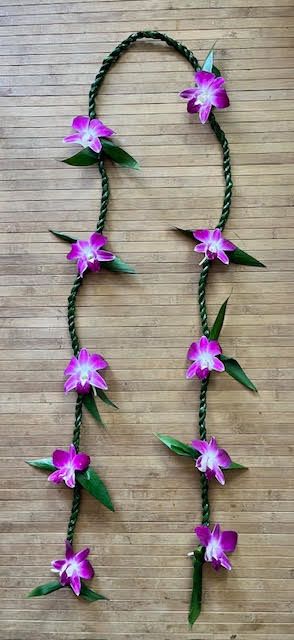 Braided floral garland with purple orchid blossoms on a wood background