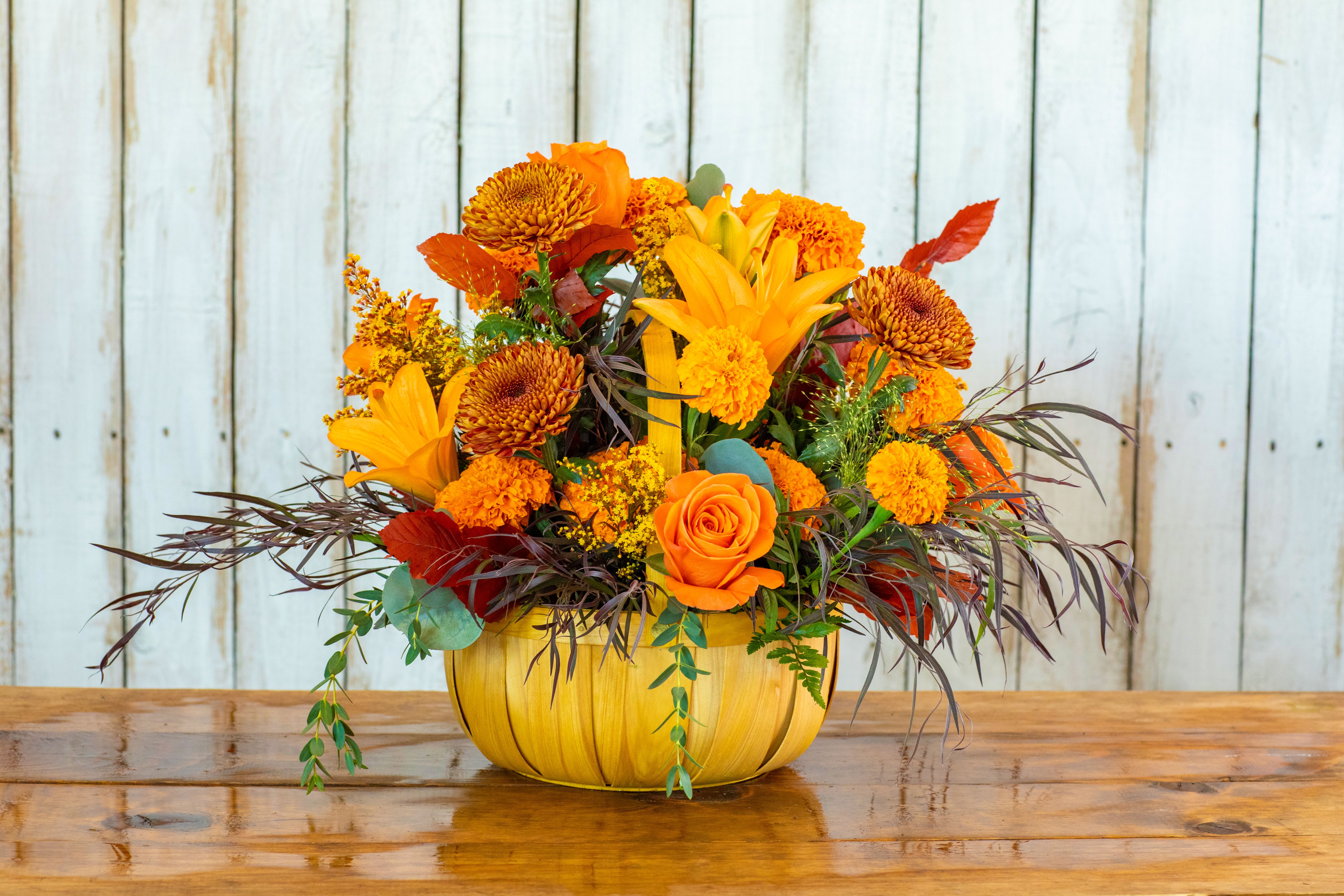 Orange and yellow floral arrangement in a pumpkin-shaped container