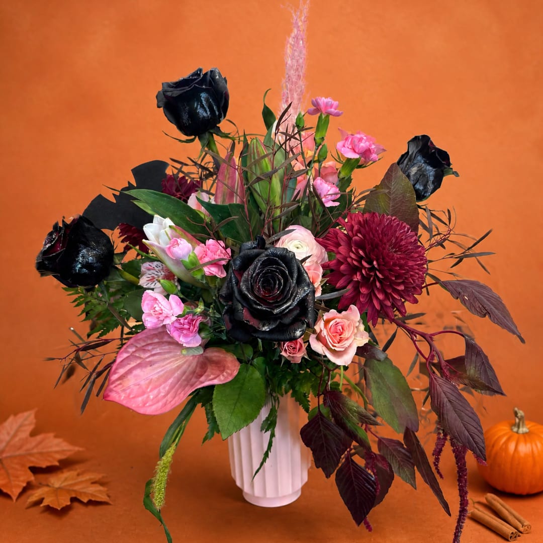 Bouquet of black and pink flowers in a white vase with autumn decor