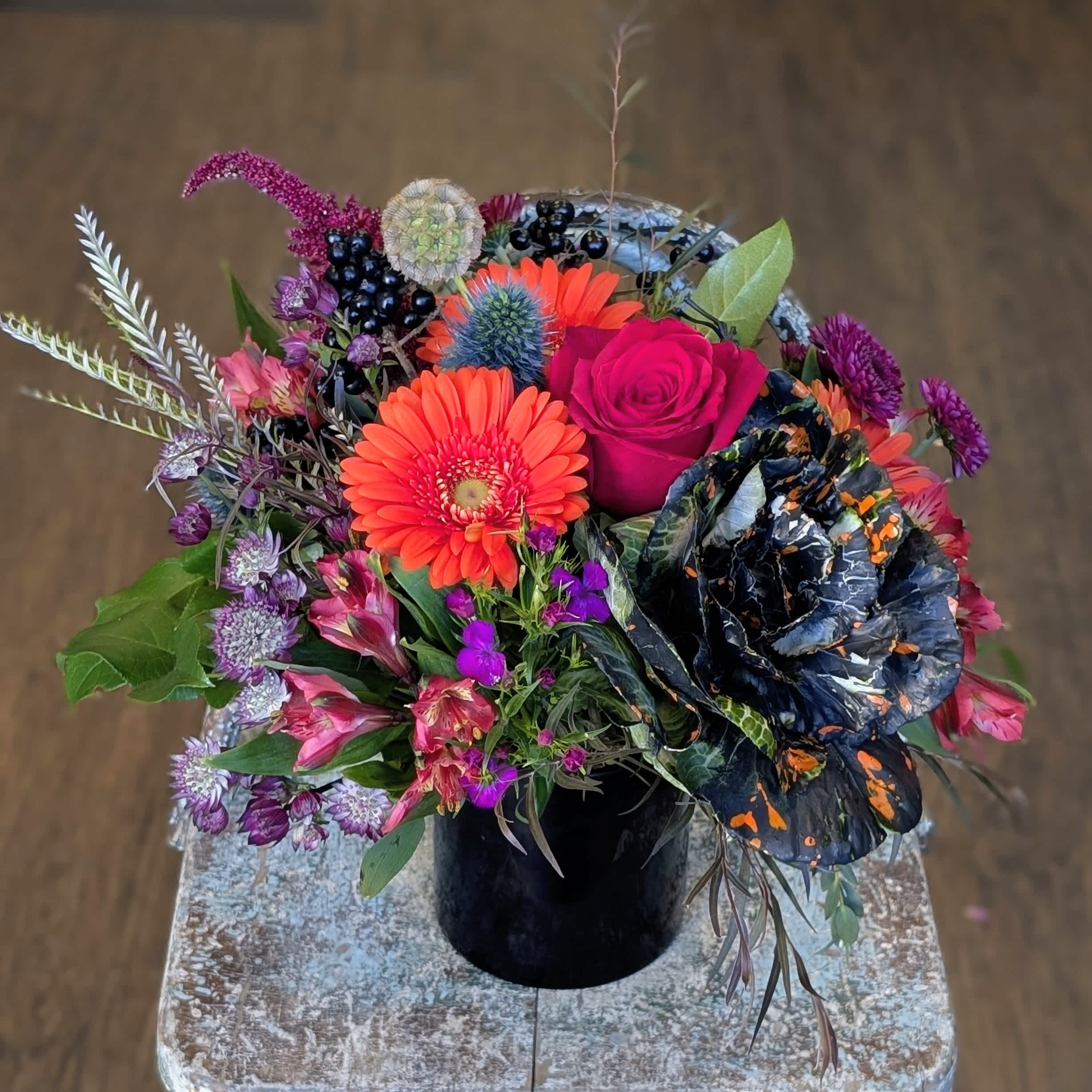 Colorful mixed bouquet in a black vase with bright pink and orange blooms
