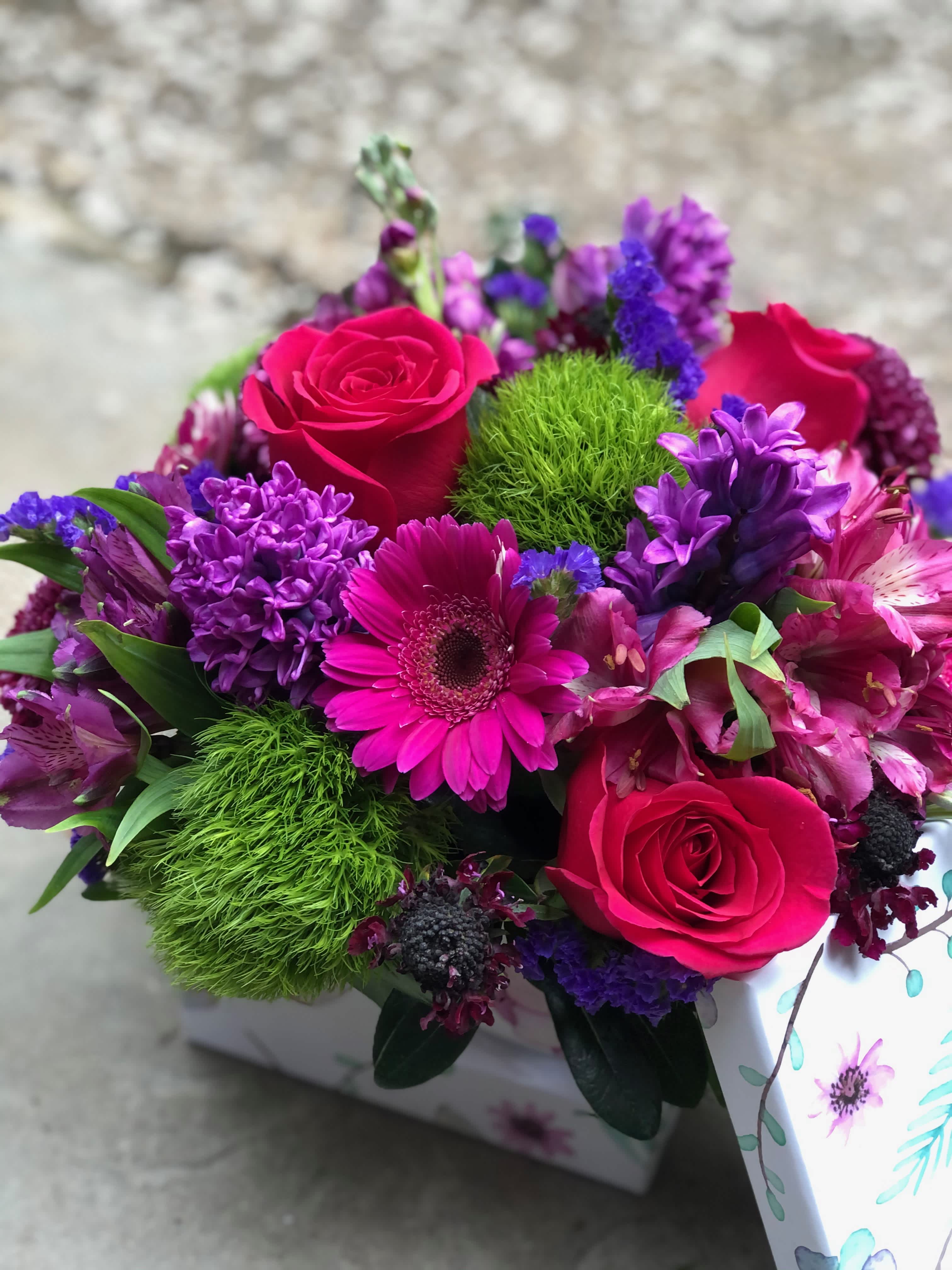 Bright pink and purple mixed bouquet in a patterned box