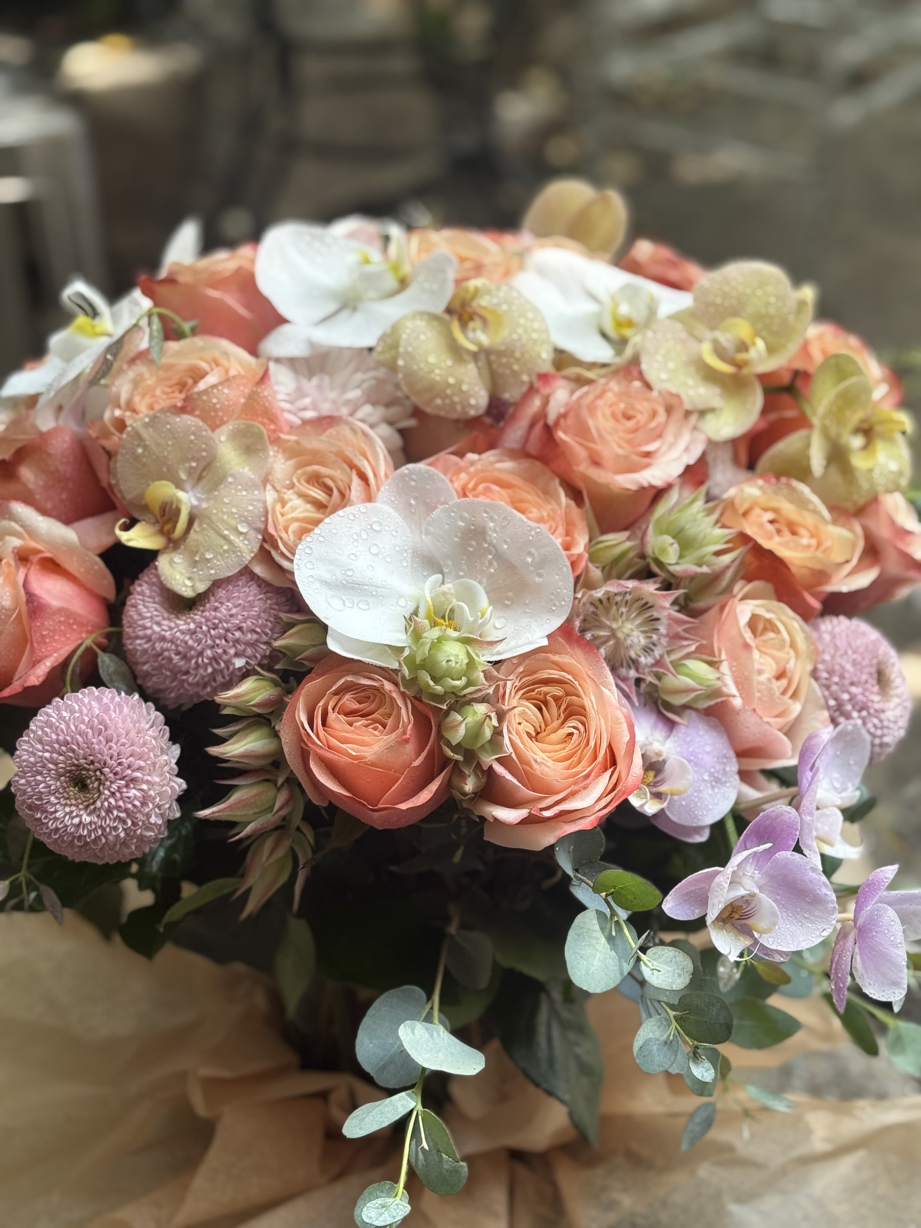 Bouquet of peach roses with white orchids and lavender pompon flowers