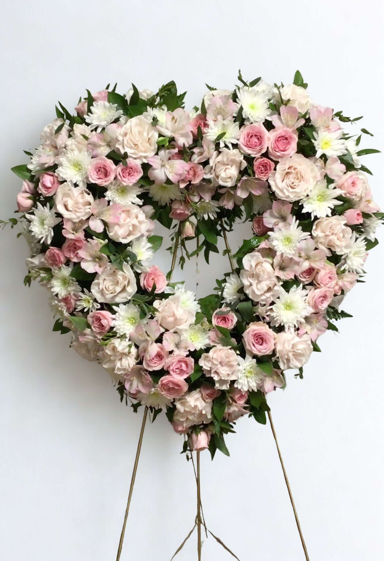 Heart-shaped floral wreath with pink and white flowers on a stand