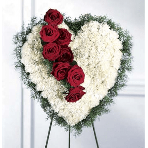Heart-shaped floral tribute with red roses and white flowers on an easel