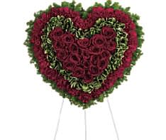 Heart-shaped floral wreath of red roses on a stand