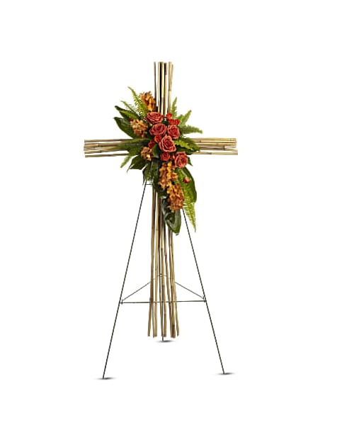 Standing floral cross with roses and greenery on a bamboo easel