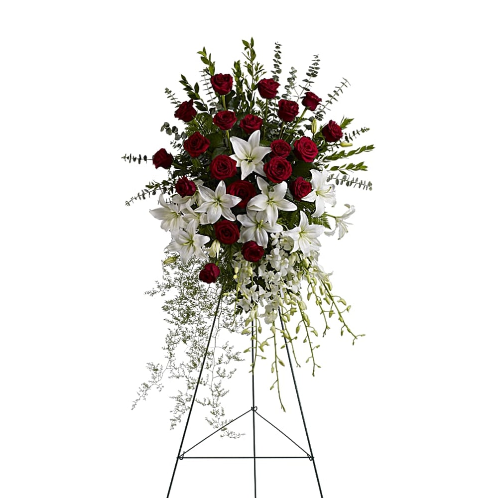 Standing floral spray with red roses and white lilies on an easel